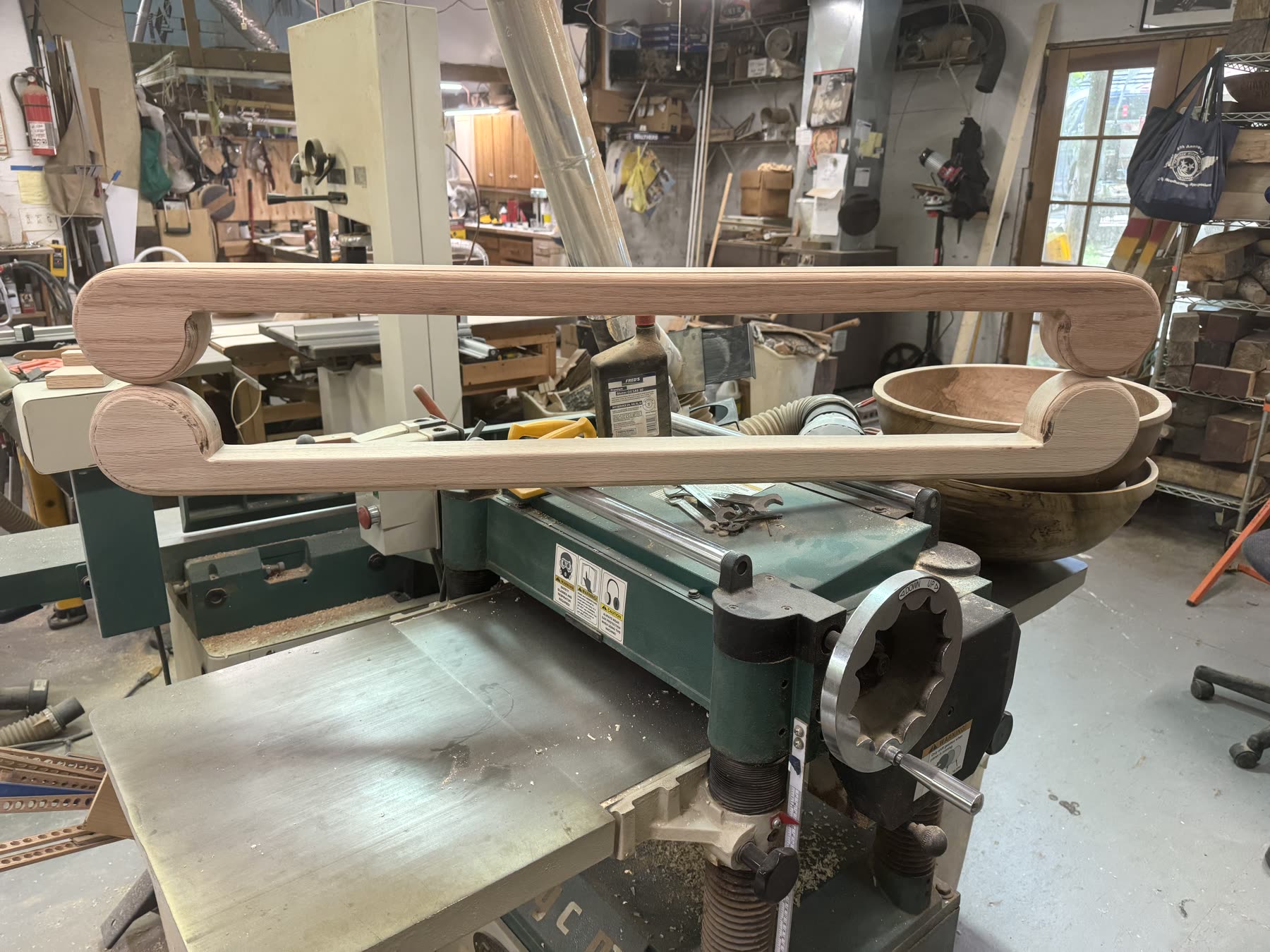 Hand-shaped white-oak volute scroll handrail terminations at the workbench
