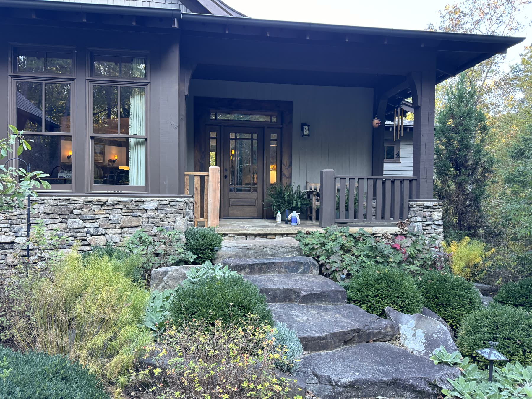 Stained cedar entry railing and gate beside dry-stacked stone columns at a Craftsman mountain home