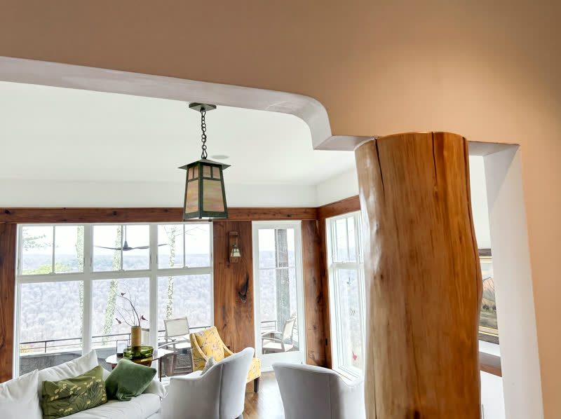 Live-edge log column and knotty-cedar trimmed window wall overlooking a forested ridgeline